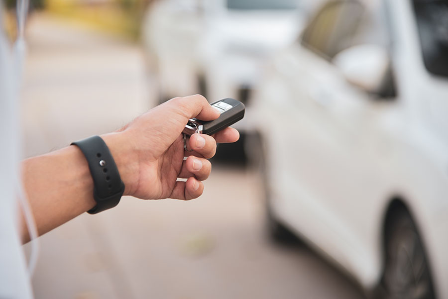 Man's hand pressing on the white car remote key